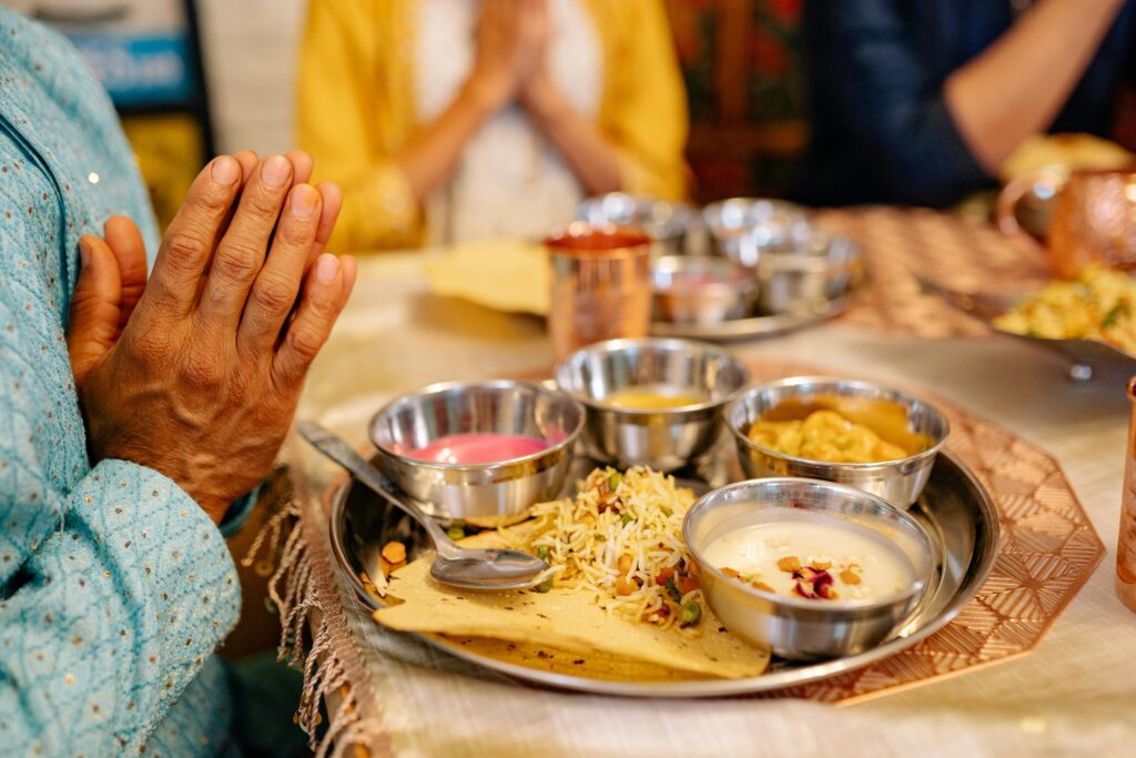 Close-up of a traditional Indian meal with hands in prayer, reflecting cultural dining rituals.